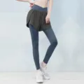 Detail view of women's fake two-piece sports leggings with high waist and running shorts. - S / Dark Gray