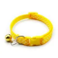Close-up detail shot of the bright yellow cat collar featuring white polka dots and gold bell. - Yellow