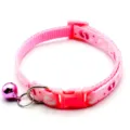 Close up of a pink pet collar with cute paw prints, plastic buckle and a shiny bell detail. - Pink
