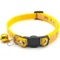 Close-up detail of yellow pet collar with cute cartoon animal prints, black buckle and golden bell. - Yellow