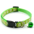 Gros plan d'un collier pour animaux vert avec motif d'empreintes, boucle et clochette. - Vert clair