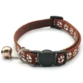 Close-up detail of brown pet cat collar with cute white paw prints and metal bell. - Coffee