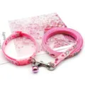 Close-up detail of pink pet leash and collar set featuring cute rabbit prints and metal bell. - Pink