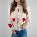 Vue détaillée du gilet en tricot crème avec des cœurs rouges, des manches longues et un nœud. - S / Abricot (Cœur)