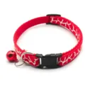 Close-up detail of red pet collar with white pattern, metal bell, and secure plastic buckle. - Red