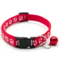 Close-up detail of the red fabric pet collar featuring white paw print patterns, black buckle, and bell. - Red