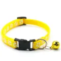 Detail view of yellow pet collar with white paw prints, black buckle and cute golden bell for small dogs. - Yellow