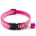 Gros plan sur le collier pour animal rose avec de jolis motifs de pattes et une clochette. - Rose rouge