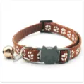 Bruine huisdierhalsband detailweergave met witte pootprintpatronen, kattenveiligheidsgesp en bel. - koffiekleur