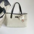 Beige canvas tote bag with black handles and plush charm, minimalist casual commuting bag. - With Pendant / Black