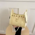Detail view of yellow quilted chain bucket bag with drawstring closure and metal hardware. - Yellow