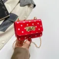 Red polka dot shoulder bag detail showing glossy patent finish, gold chain strap, and lock. - Red Polka Dot
