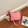 Detail view of pink woven shoulder bag with cute plush dog pendant and stylish strap design. - Pink With Charm