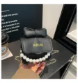 Bolso cruzado negro para niña con lazo, asa de perlas y cadena dorada. Cartera infantil. - Negro