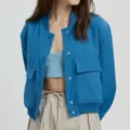 Close-up detail of women's casual blue snap-button jacket with utility pockets and ribbed trim. - Teal