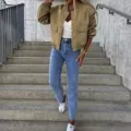 Outdoor detail shot of casual khaki bomber jacket with flap pockets worn on concrete stairs. - Olive Green