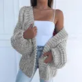 Detail view of a cozy grey chunky cable knit cardigan, perfect for layering and winter warmth. - Gray