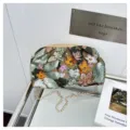 Primo piano di una elegante borsa pochette ricamata con fiori di paillettes e catena d'oro. - Verde