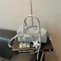 Close-up of stylish light blue denim Boston handbag with silver handle and star charm detail. - With Pendant / Silver