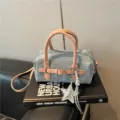 Detail view of a chic blue denim Boston bag with pink leather handles and silver star charm. - With Pendant / Pink