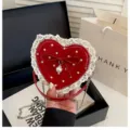 Vue détaillée du sac à bandoulière rouge en forme de cœur avec dentelle et perle mignonne. - Rouge