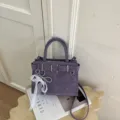Borsa a mano e tracolla elegante viola in pelle sintetica con fibbia e ciondolo di perle. - Viola