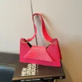 Detailed view of a stylish pink crocodile pattern shoulder bag with a unique geometric design. - Pink
