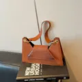 Detailed view of brown crocodile pattern crossbody bag with chic metallic ring accents. - Brown