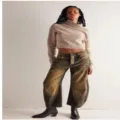 Detailed view of women's vintage distressed wide-leg jeans paired with a cropped turtleneck sweater. - Caramel color