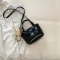 Elegante borsa secchiello in pelle verniciata nera con fiocco e grazioso orsetto. - Nero