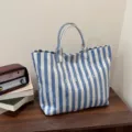 Blue and white striped canvas tote bag detail, featuring clear large capacity and dual handles. - Blue