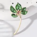 Elegant vintage lotus brooch with green enamel leaves, golden stem, and delicate pearl accents. - Green
