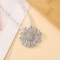 Close-up detail of a sparkling silver sunflower flower charm attached to a white twisted rope. - Sunflower Silver Necklace