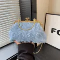 Dettaglio della borsa da sera blu con rose in rete, chiusura dorata e catena raffinata. - Blu