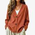 Dettaglio in primo piano del cardigan elegante a maniche lunghe in velluto a coste ruggine. - arancio-rosso