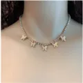 Primo piano dettagliato della collana tennis in strass scintillante con cinque ciondoli a farfalla. - Oro Con Strass Bianco