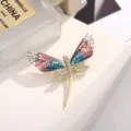 Detail view of a stunning dragonfly brooch featuring rhinestone body and gradient acrylic wings. - Purple