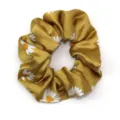 Detailopname van een mosterdgeel satin haarelastiek met een schattige witte madeliefjesprint. - Geel