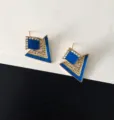 Close-up van geometrische blauwe strass oorbellen, minimalistisch sieradendetail. - Saffierblauw