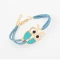 Charmante blauwe suède uilenarmband met turquoise emaille vleugels en gouden details. - Blauw
