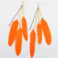 Gedetailleerd overzicht van oranje veren kwast oorbellen met metalen kettingen voor boho stijl. - Oranje