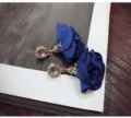 Close-up detail of royal blue fabric rose earrings with sparkling rhinestone stud design. - Blue