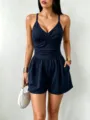 Close-up detail shot of women's navy blue sleeveless wrap-front romper with side pockets. - Navy Blue