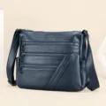 Klassieke donkerblauwe lederen dames schoudertas met meerdere ritsvakken en verstelbare schouderriem. - Blauw