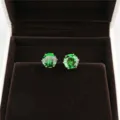 Detailed close-up of vibrant green round 8mm cubic zirconia stud earrings in a velvet box. - Gold & Green