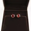 Close-up detail shot of red round 8mm cubic zirconia stud earrings in a luxury brown velvet box. - Silver + Red