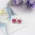 Gedetailleerde close-up van de sprankelende roze strass roos oorbellen met fijne metalen bloemtextuur. - Roze