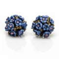 Detailopname van blauwe keramische bloem oorknopjes oorbellen met fonkelende strass steentjes. - Blauw