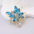 Blue crystal flower brooch detail view, golden metal alloy with sparkling rhinestones. - Gold