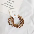 Close-up detail van golvende haarscrunchies in bruin en beige, elastische haaraccessoires. - 4 Stuks/Verpakking / Bruin